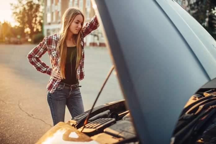 Car breakdown concept, woman against open hood